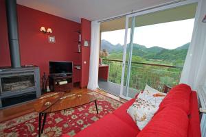 a living room with a red couch and a large window at Baigorri in El Llano
