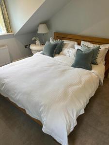 a large white bed with green pillows on it at The Croft in Cowbridge +26 photos
