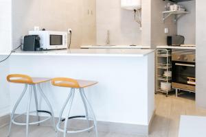 a kitchen with a white counter and two stools at Lisboa - Arroios Central Apartment in Lisbon