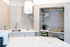 a white kitchen with a sink and a stove at Lisboa - Arroios Central Apartment in Lisbon