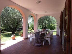 un patio extérieur avec des tables, des chaises et des arbres dans l'établissement Canal di Bocco villa tra 5 terre e Versilia, à Luni