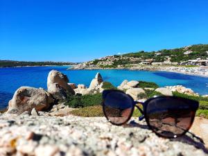 Para okularów słonecznych siedzących na kamienistej plaży w obiekcie La Residenza del Porto w mieście Santa Teresa Gallura +2 zdjęcia