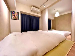 a large white bed in a room with a window at 浅草寺3分 浅草駅6分 2寝室+リビング2-6人 スカイツリービュー 駅近 成田空港&羽田空港直通 in Tokyo