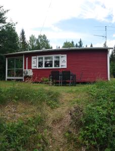 uma casa vermelha com uma mesa e cadeiras em frente em Stuga vad vatten em Åsarp