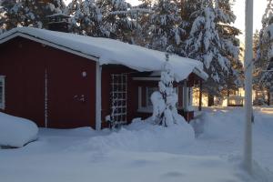 Cabaña cubierta de nieve con techo cubierto de nieve en Lysti Cottage by the lake and magical countryside, en Rovaniemi