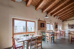 a dining room with tables and chairs and windows at Rifugio Galaberna in Ostana