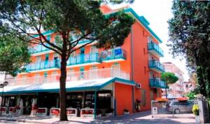 um grande edifício laranja com uma árvore em frente em Hotel Altinate em Lido di Jesolo