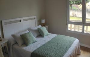 a bedroom with a bed with green pillows and a window at Amaral Miramar in Boiro