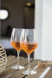 dos copas de vino sentadas sobre una mesa de madera en Sunrise Sardinia Posada, en Posada