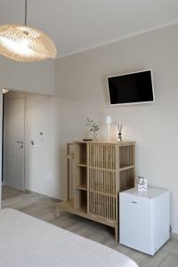 1 dormitorio con TV en una pared blanca en Sunrise Sardinia Posada, en Posada