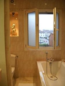 ein Bad mit einer Badewanne und einem Fenster in der Unterkunft Hôtel de la cloche in Vitry-le-François