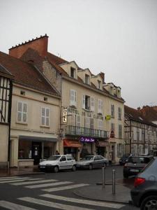 eine Stadtstraße mit Autos, die vor den Gebäuden geparkt sind in der Unterkunft Hôtel de la cloche in Vitry-le-François