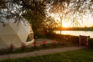 une tente en face d'un lac avec le coucher du soleil dans l'établissement Dôme avec vue sur Loire proche de Chambord, à Saint-Dyé-sur-Loire