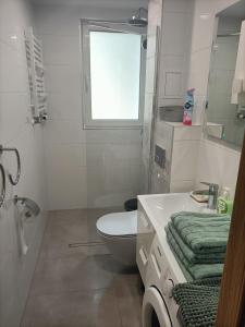 een witte badkamer met een toilet en een raam bij Apartament ALE LABA in Kołobrzeg