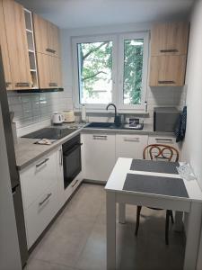 cocina con armarios blancos, mesa y ventana en Apartament ALE LABA, en Kołobrzeg