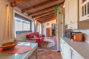 een keuken en een woonkamer met een rode stoel en een bank bij Villetta la Colombaia in Carzano