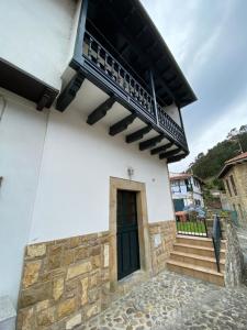 a building with a black door and a balcony at Casa Gin Tazones in Tazones