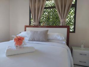 a white bed with a flower in a vase on it at Reef Hills Residence FAMILY HOME in Au Cap