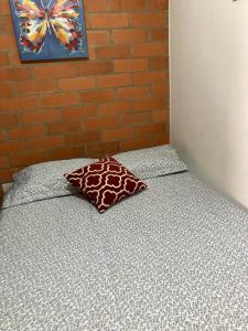 1 cama con almohada y pared de ladrillo en Casa Roma - La tranquilidad del campo en la Ciudad - RNT 1 0 8 1 3 7-, en Salento