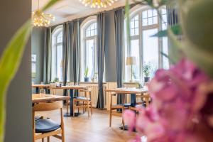 un restaurante con mesas, sillas y ventanas en Hostrups Hotel, en Tønder