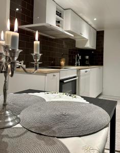 een keuken met witte kasten en een tafel met kaarsen bij Nyrenoverat boende i villaområde in Gävle