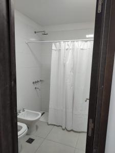 uma casa de banho com uma cortina de chuveiro branca e um WC. em Temporario catamarca em San Fernando del Valle de Catamarca