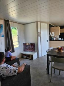 un hombre y una mujer sentados en una sala viendo la tele en Chalet avec piscine, climatisation & vue de 2 à 6 personnes - Hasparren - Pays Basque - Chalet Ibaia, en Hasparren