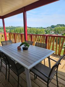 una mesa de madera en una terraza con sillas en Chalet avec piscine, climatisation & vue de 2 à 6 personnes - Hasparren - Pays Basque - Chalet Ibaia en Hasparren