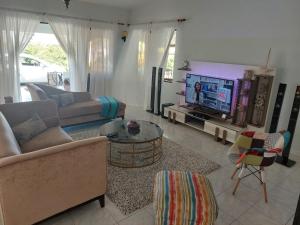 een woonkamer met een bank en een tv bij Reef Hills Residence FAMILY HOME in Au Cap