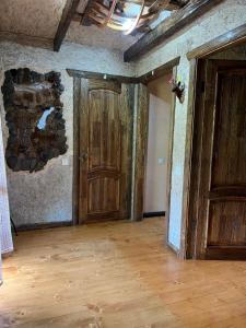 ein altes Zimmer mit einer Holztür und Holzböden in der Unterkunft Zelenyj Raj in Pashkivtsi