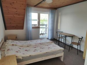 um quarto com uma cama, uma mesa e uma janela em Stara Plaża em Mikolajki