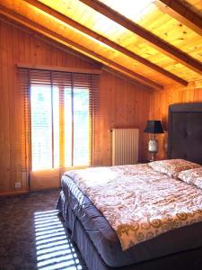 Chalet Bellevue, Villars-sur-Ollon في Ollon: غرفة نوم بسرير كبير في غرفة بجدران خشبية