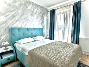 een slaapkamer met een blauw bed en een groot raam bij 4FriendsCoresiBrasov Blue in Braşov