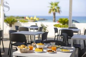 una tavola con piatti di cibo sopra con l'oceano sullo sfondo di Sud Hotel Pulsano a Pulsano