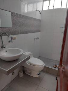 ein Badezimmer mit einem weißen WC und einem Waschbecken in der Unterkunft Casa completa, 5 dormitorios y jardín in Ayacucho