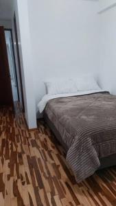 a bedroom with a bed and a wooden floor at Casa completa, 5 dormitorios y jardín in Ayacucho