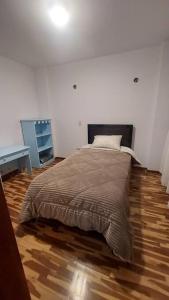 1 dormitorio con 1 cama y suelo de madera en Casa completa, 5 dormitorios y jardín, en Ayacucho