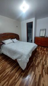 a bedroom with a bed and a wooden floor at Casa completa, 5 dormitorios y jardín in Ayacucho