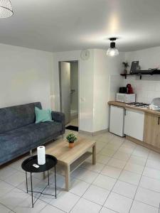ein Wohnzimmer mit einem Sofa und einem Tisch sowie eine Küche in der Unterkunft L'idéal séjour avec jardin privé proche Paris gare et commerce in Sarcelles