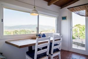 una sala da pranzo con tavolo, sedie e finestre di El Refugio del Viento, Casita Levante a Facinas