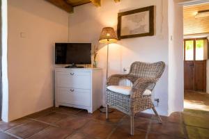 a wicker chair and a television in a room at El Refugio del Viento, Casita Levante con Jardín y Piscina in Facinas