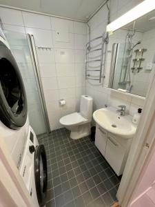 y baño con aseo, lavabo y lavadora. en Hogland Apartments - 2, en Kotka