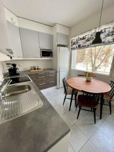 cocina con mesa de madera y cocina con fregadero en Hogland Apartments - 2, en Kotka