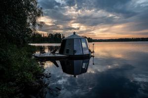 a boat on a lake with the sun setting at Luxury Aurora glass Igloo, hot tub & sauna cottage in Rovaniemi +35 photos