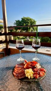 a plate of bacon and two glasses of wine at Anemos Pelion Seaview in Kala Nera