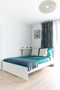 um quarto branco com uma cama com lençóis e almofadas azuis em Le Citadin-T1-28m2-Pte Paris M7 em Le Kremlin-Bicêtre