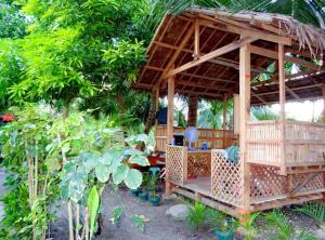 Cabaña de bambú pequeña con mesa en el jardín en Summer Guest House, en Moalboal
