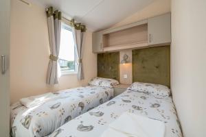 2 letti in una piccola camera da letto con finestra di 3 Bed Static Caravan-Seton Sands a Longniddry