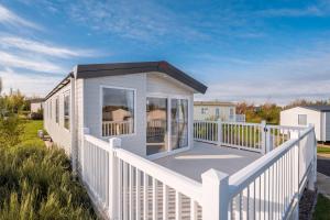 a small white house with a white fence at 3 Bed Static Caravan-Seton Sands in Longniddry