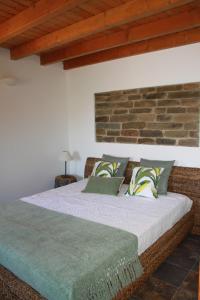 een bed in een kamer met een bakstenen muur bij Corvatos Casas do Monte in Almodôvar